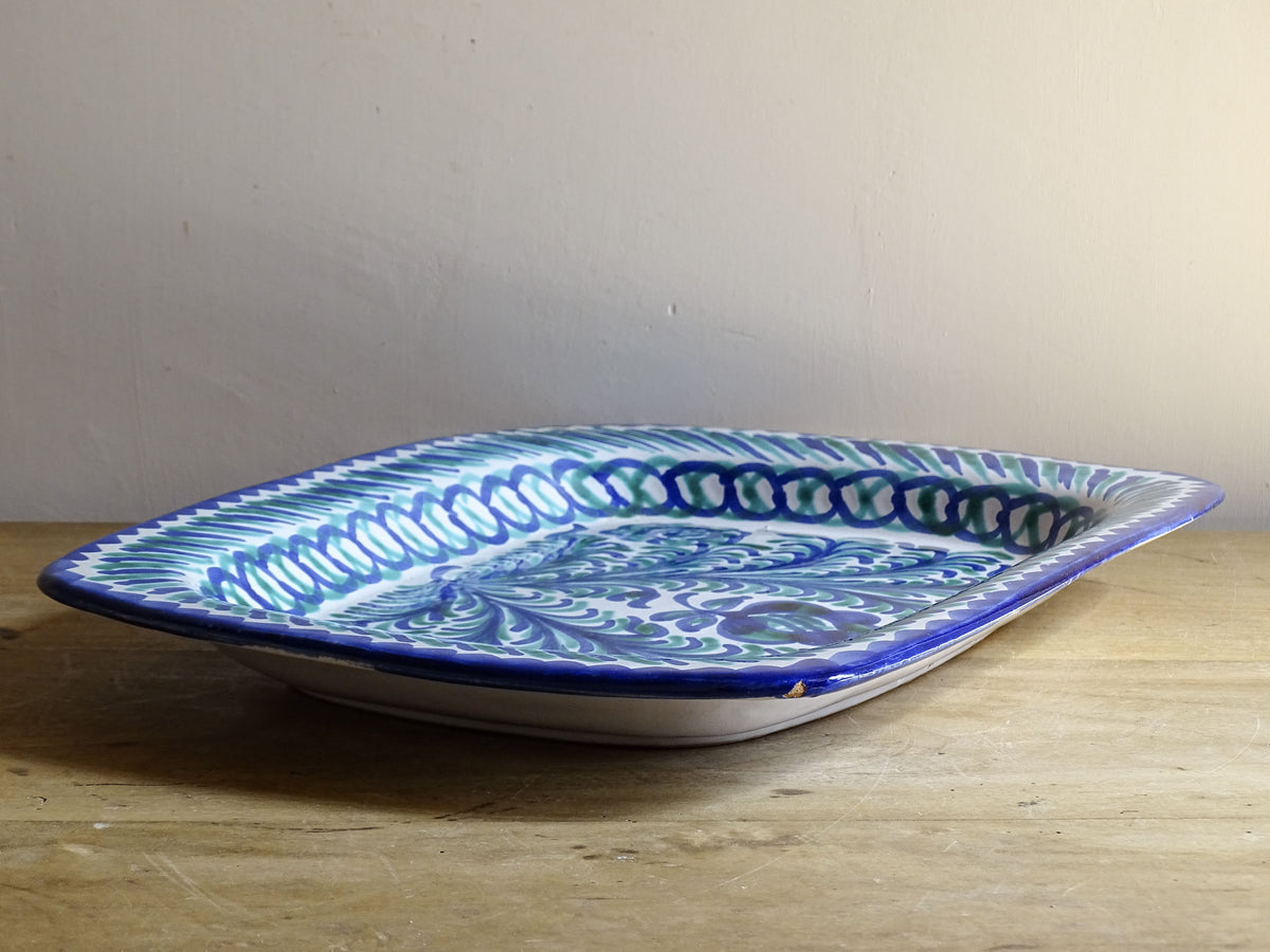 A striking Spanish vintage Fajalauza platter, hand-painted in cobalt blue and soft green on a white ground. The design features flowing foliate motifs and stylised floral details.