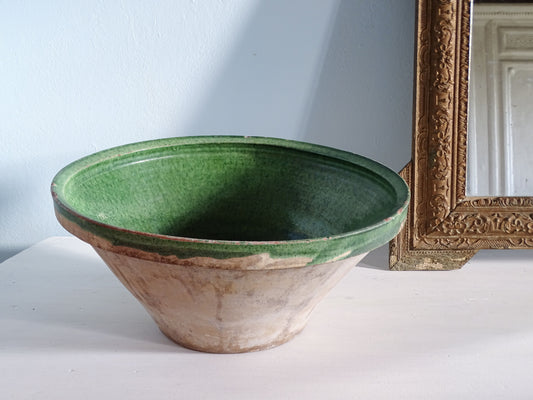 French antique tian bowl with a green glaze interior and unglazed earthenware exterior. Pictured next to a gold mirror in front of a pale blue wall