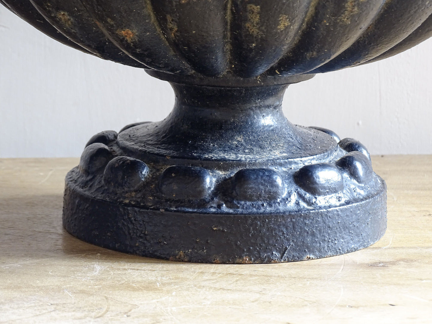 A pair of French antique cast iron garden urns, dating to the late 19th century. Cast in a classic campana form, each urn features a deeply gadrooned body, a softly moulded rim and a stepped pedestal base.
