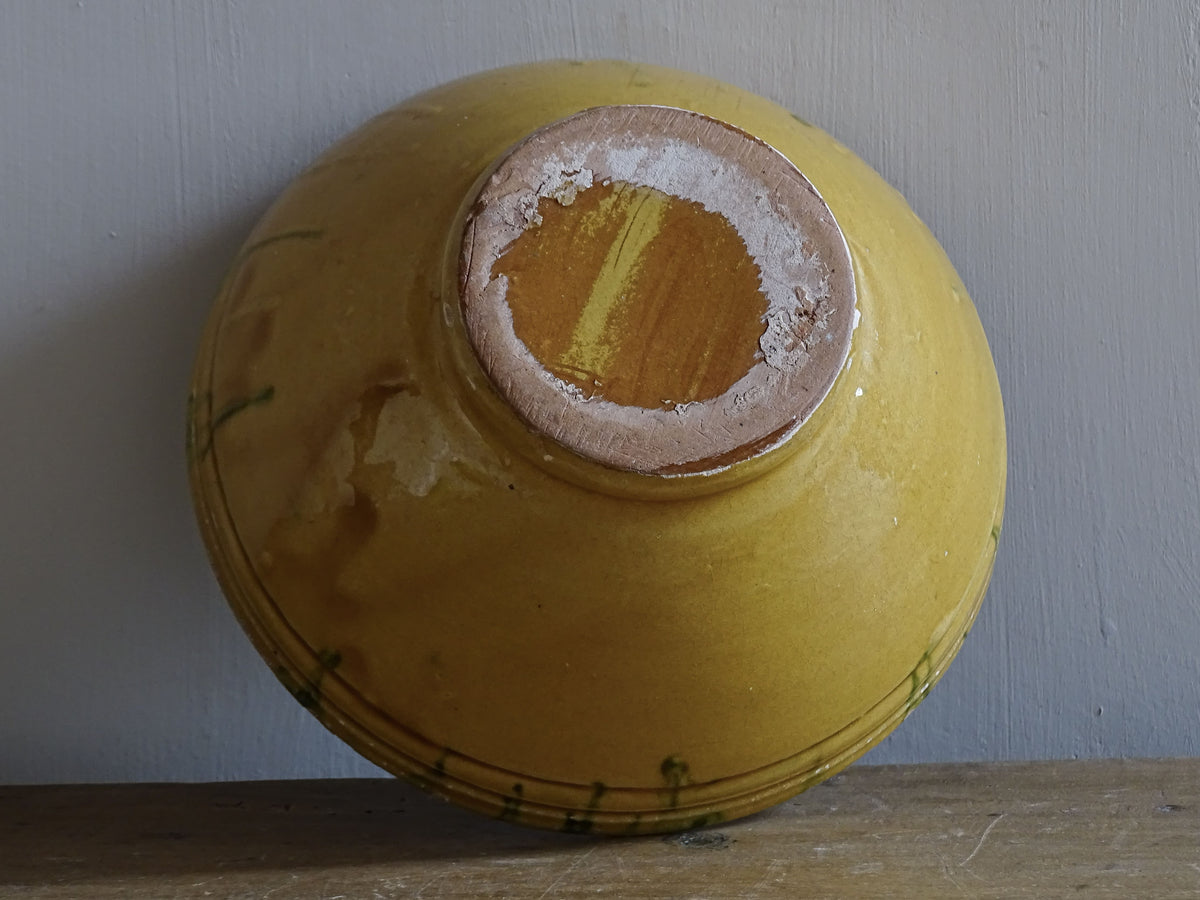 A small French antique terracotta bowl with a striking yellow ochre glaze and a traditional green jaspé decorated interior. Hand-thrown in earthenware.