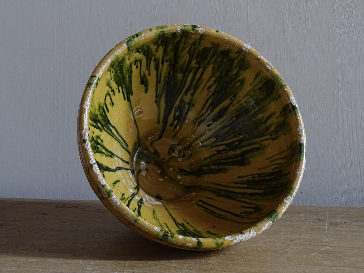 A small French antique terracotta bowl with a striking yellow ochre glaze and a traditional green jaspé decorated interior. Hand-thrown in earthenware.