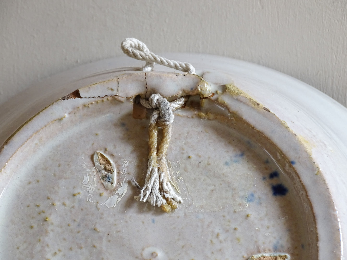 Close-up of the underside of a vintage Fajalauza bowl, showing glaze marks, firing imperfections and an old hanging cord.