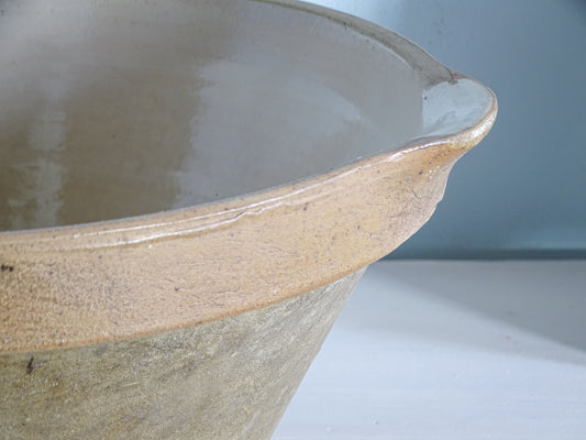 Detail of the shaped pouring spout and caramel-coloured glazed rim on a French stoneware kitchen bowl.