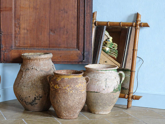 French antique earthenware pots including a ponne and confit pots in a blue painted room in a French country house.