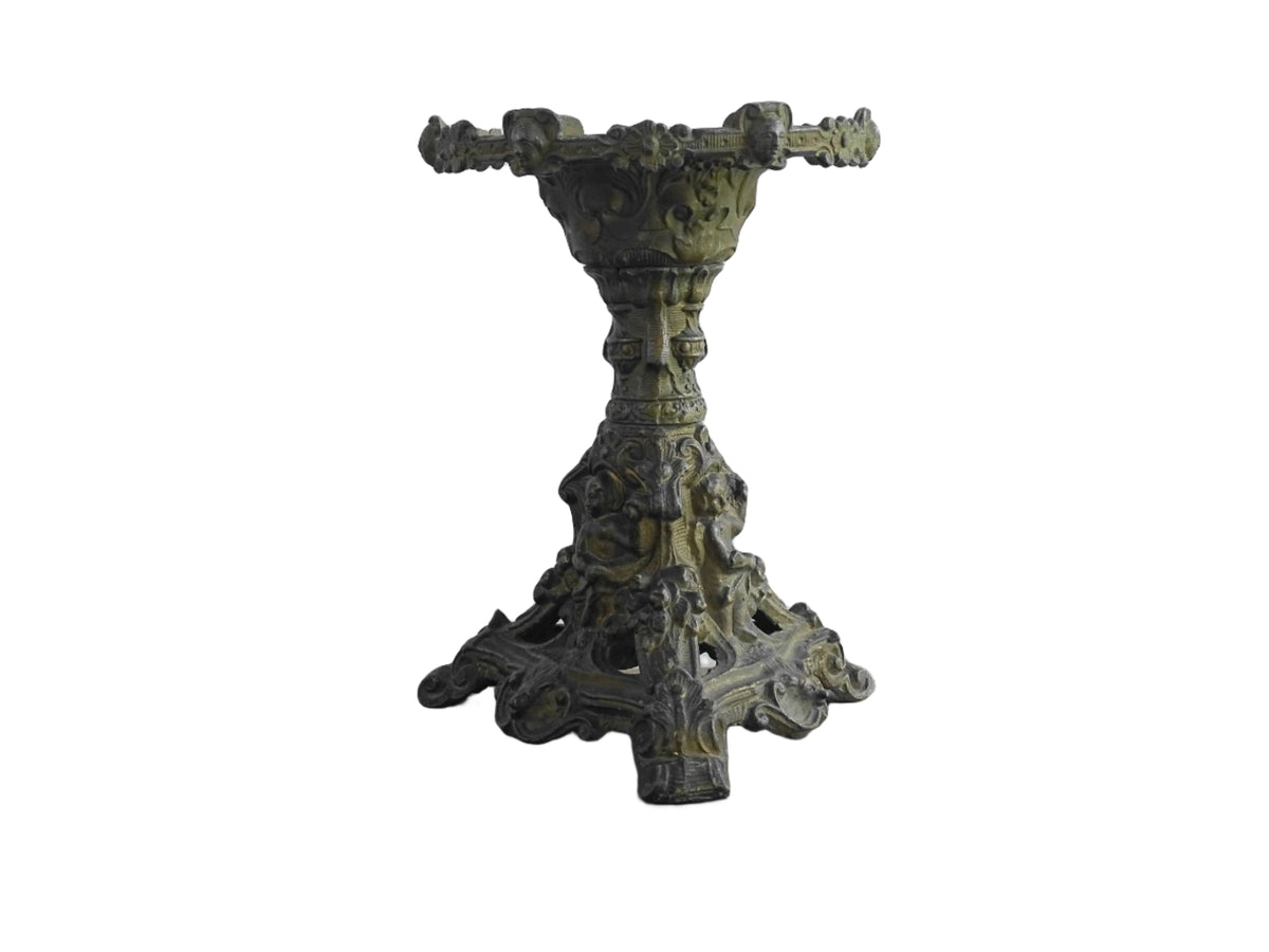 Ornate French antique cast iron candle holder with tripod base and decorated with cherubs.