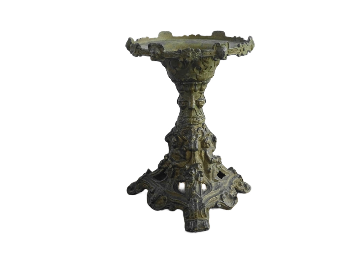Ornate French antique cast iron candle holder with tripod base and decorated with cherubs.
