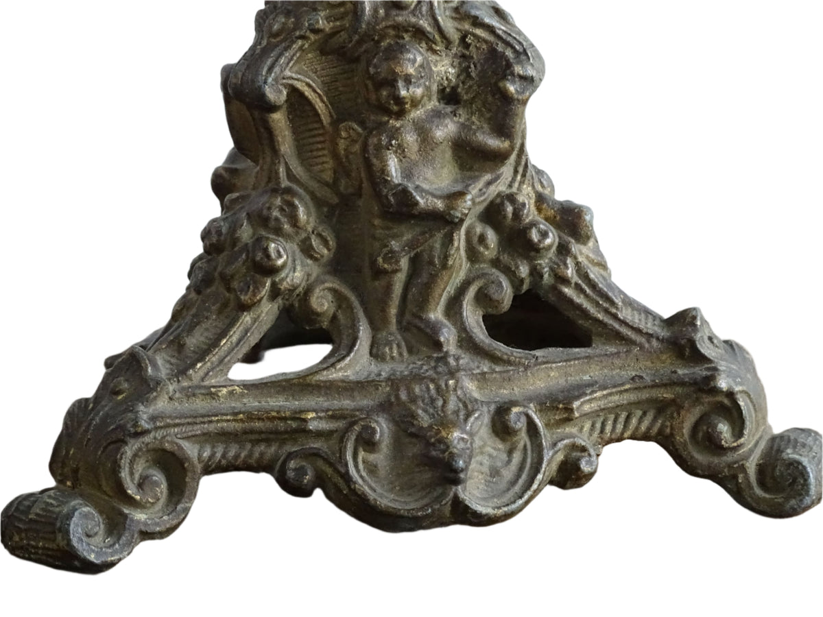 Ornate French antique cast iron candle holder with tripod base and decorated with cherubs.