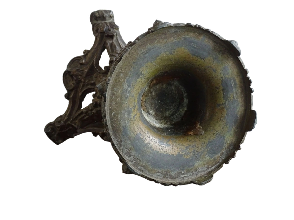 Ornate French antique cast iron candle holder with tripod base and decorated with cherubs.
