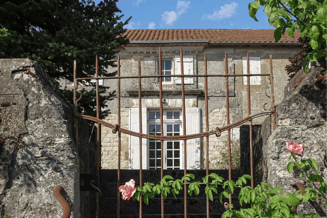 French country house in South West France seen through an old iron garden gate in summer