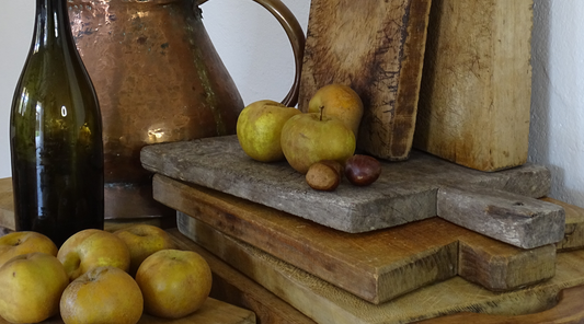 Antique French farmhouse accents, a copper jug, a pile of antique cutting boards with patina. 