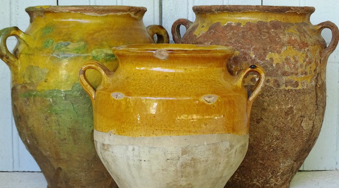 Antique French confit pots with yellow glaze in front of a painted blue shutter