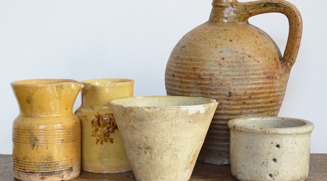 French antique pottery including glazed pitchers, terracotta jugs, a pottery faisselle and a resin pot. 