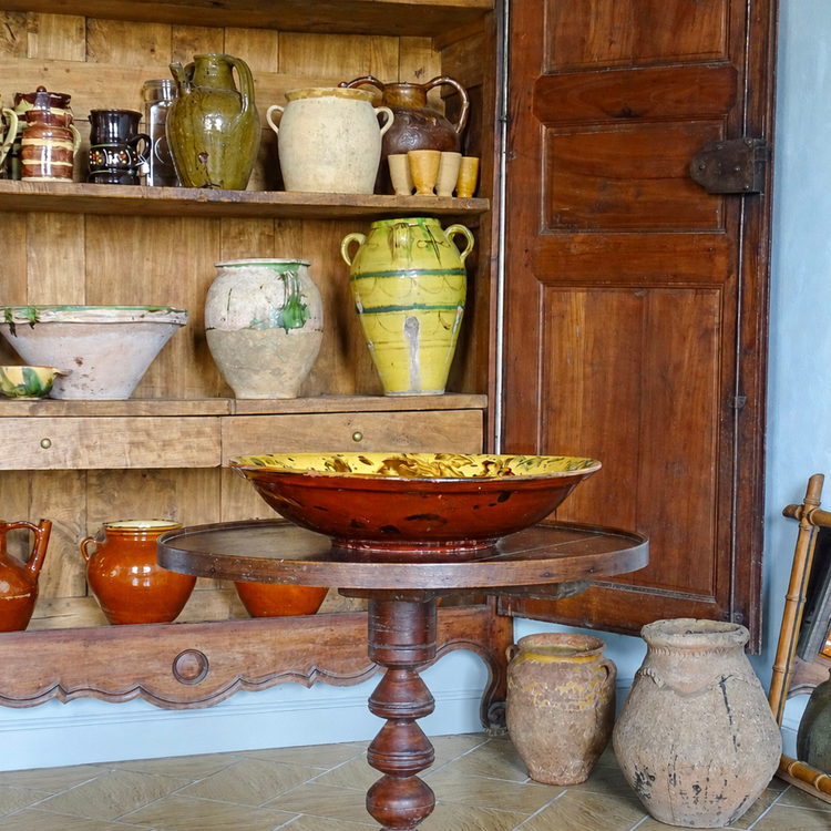 Antique pottery in a wooden armoire in French country house