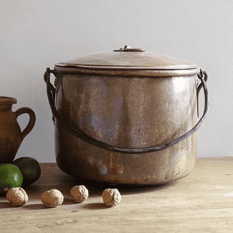 French antique copper cooking pot on a wooden table with walnuts