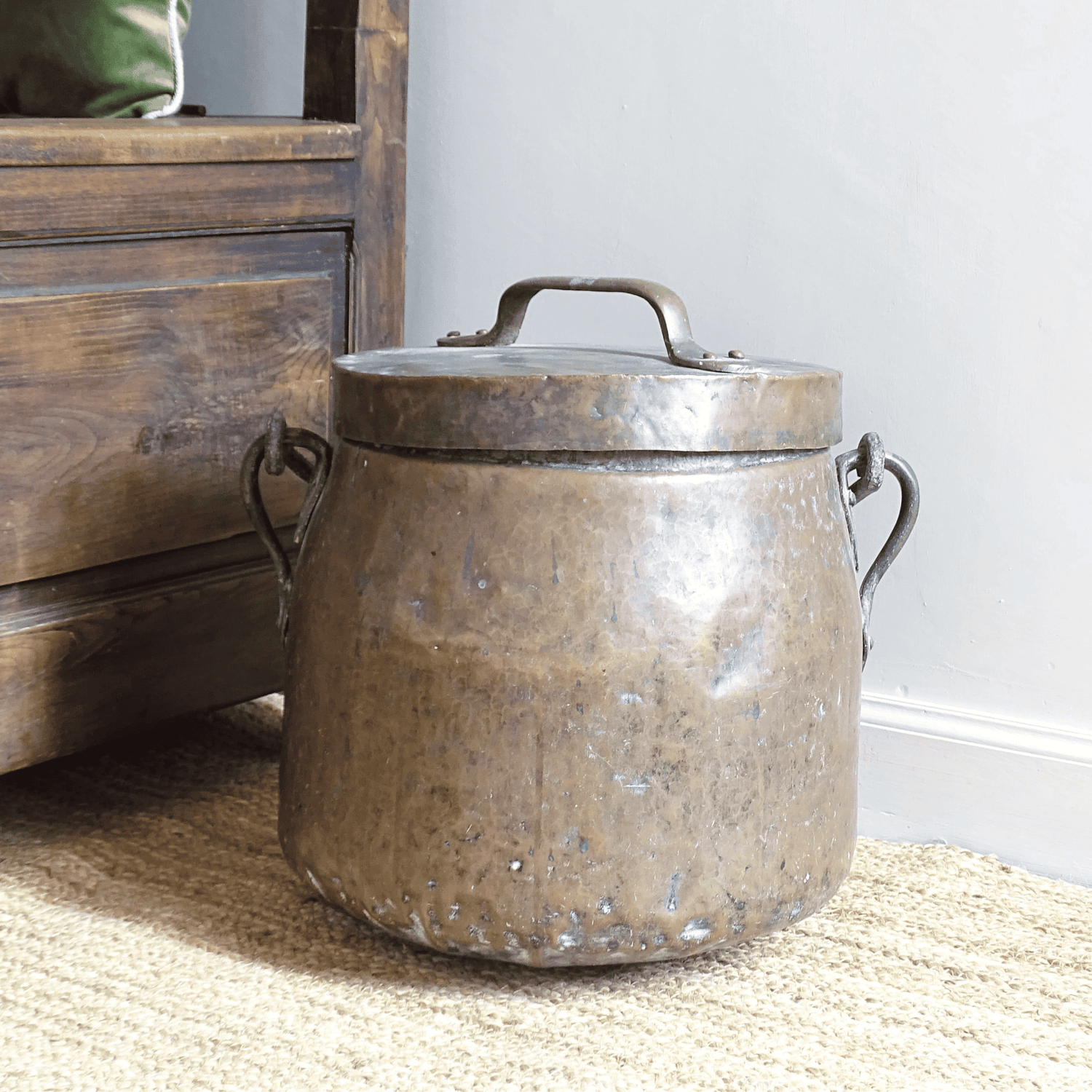 Large French antique copper cauldron on a jute rug next to an antique wooden chair