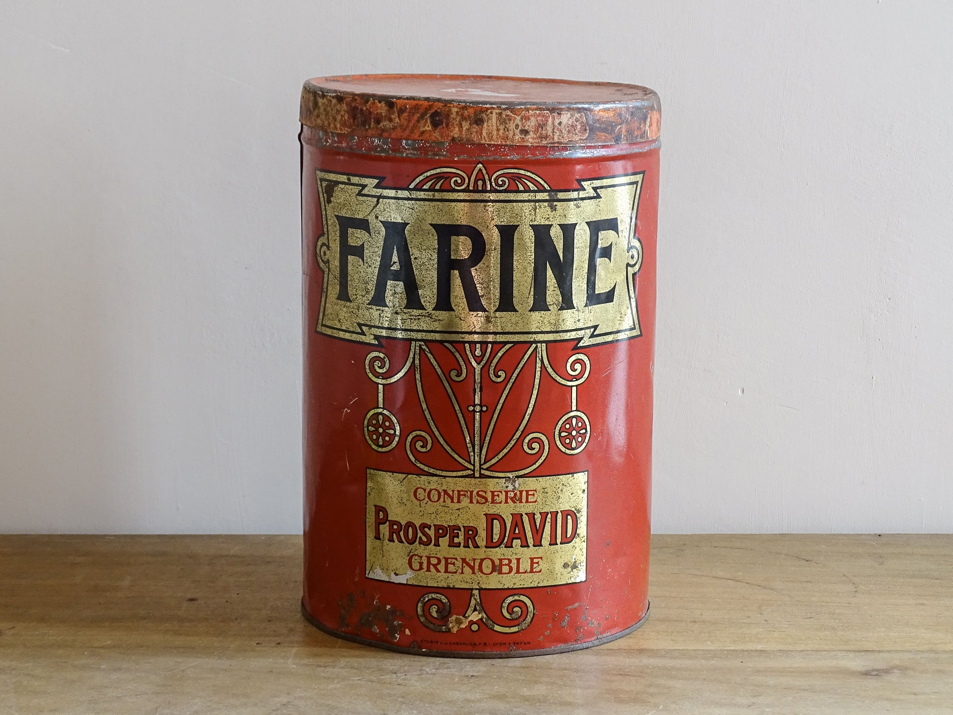 Vintage red Farine can with gold and black text on a wooden surface.