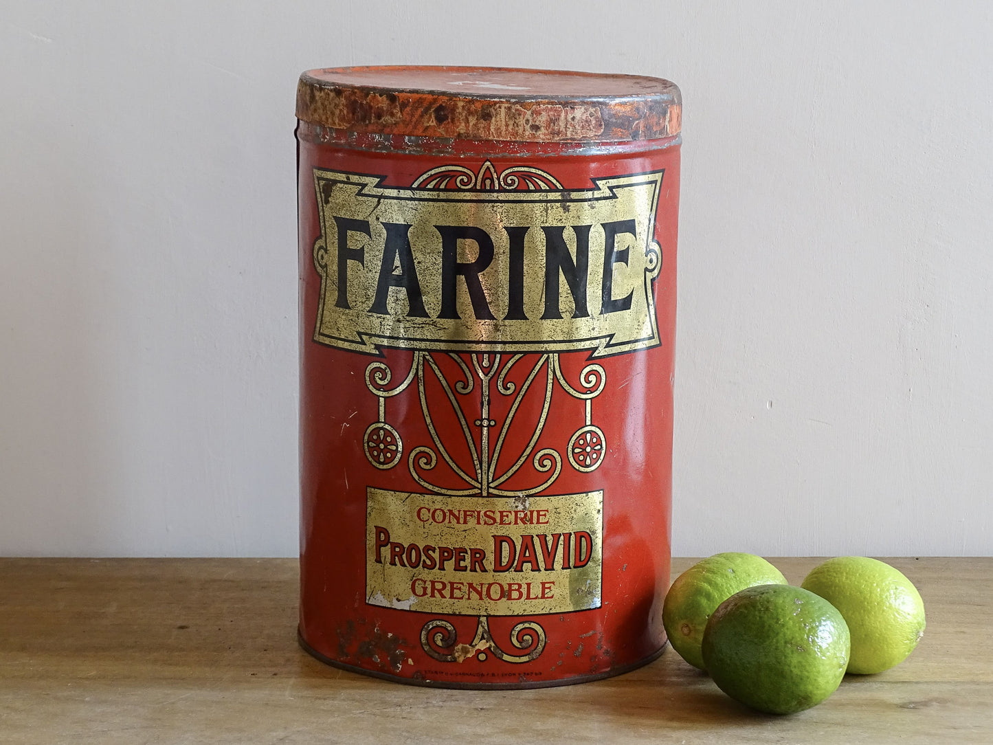 Vintage red Farine canister with green limes on a wooden surface