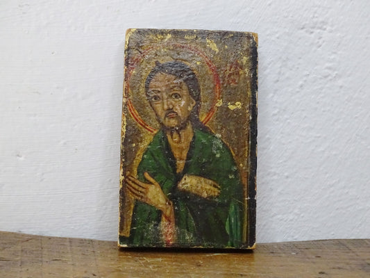 An antique Christian icon painted on wood, featuring a saint with a halo and a green robe. Ideal for religious decor and spiritual displays in a home.