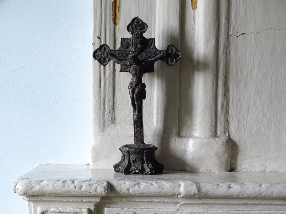 French antique holy water font in plaster, displayed on a country house fireplace next to a pale blue wall. 