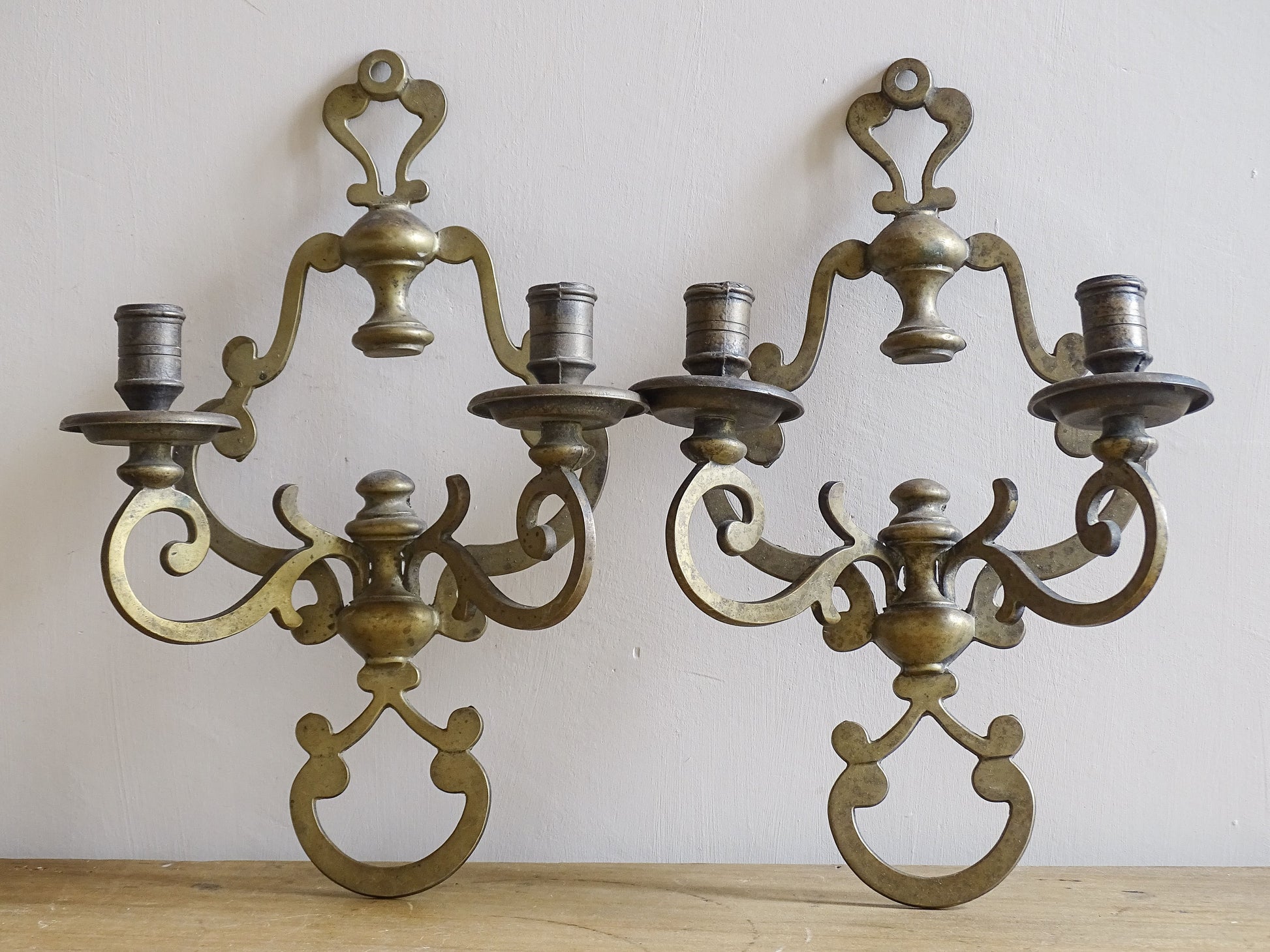 Pair of ornate brass wall sconces on a plain background