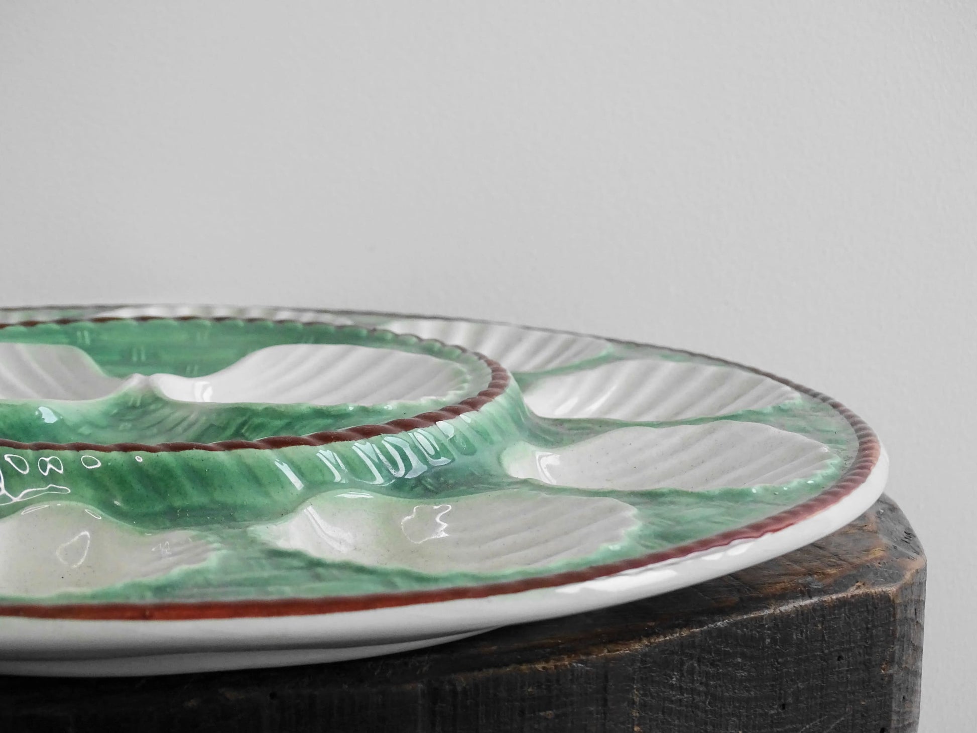 Vintage French barbotine oyster serving plate with space for twelve oysters, dating to around the 1930s. It has a green, basketweave design with a brown edge