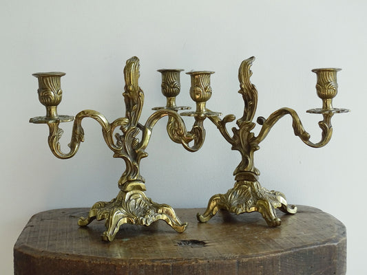 Pair of French antique brass candelabras in a rococo style. Early 20th century antique candelabras with space for two tapered candlesticks. Brass candle holders for dining table decor or living room decor.