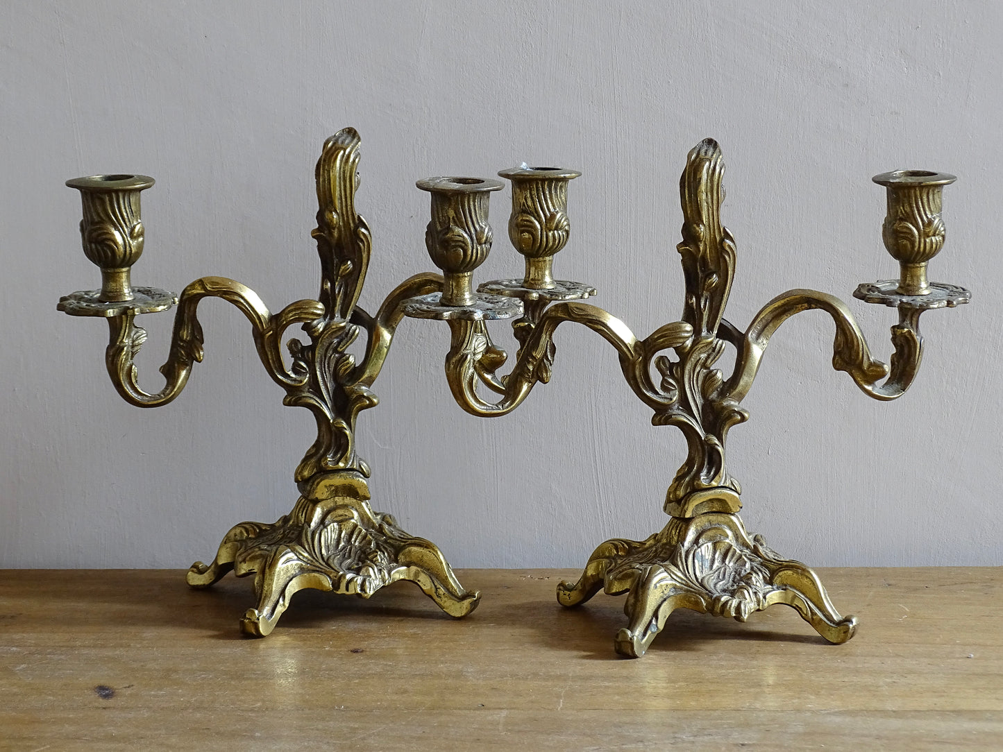 Pair of French antique brass candelabras in a rococo style. Early 20th century antique candelabras with space for two tapered candlesticks. Brass candle holders for dining table decor or living room decor.