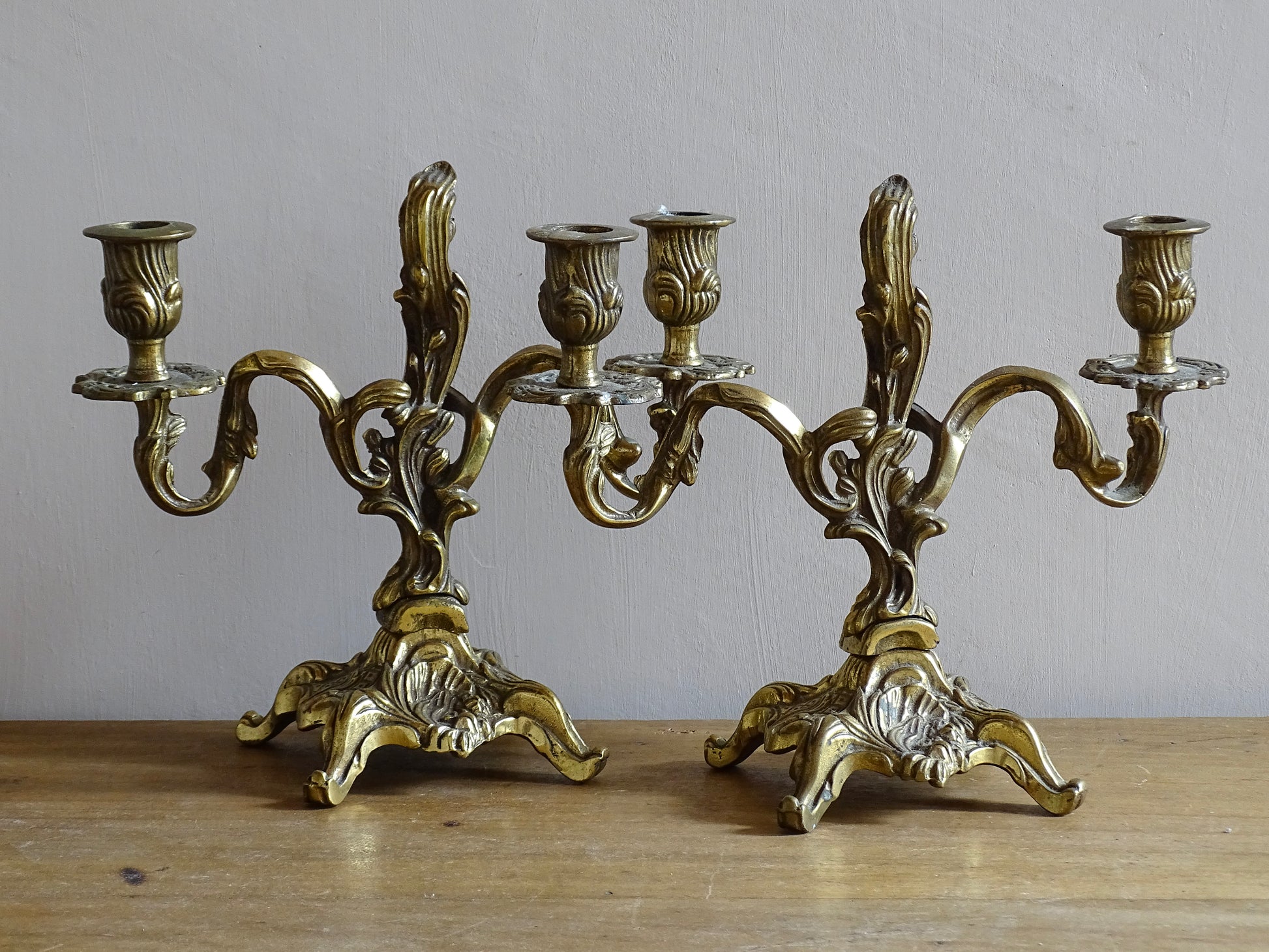 Pair of French antique brass candelabras in a rococo style. Early 20th century antique candelabras with space for two tapered candlesticks. Brass candle holders for dining table decor or living room decor.