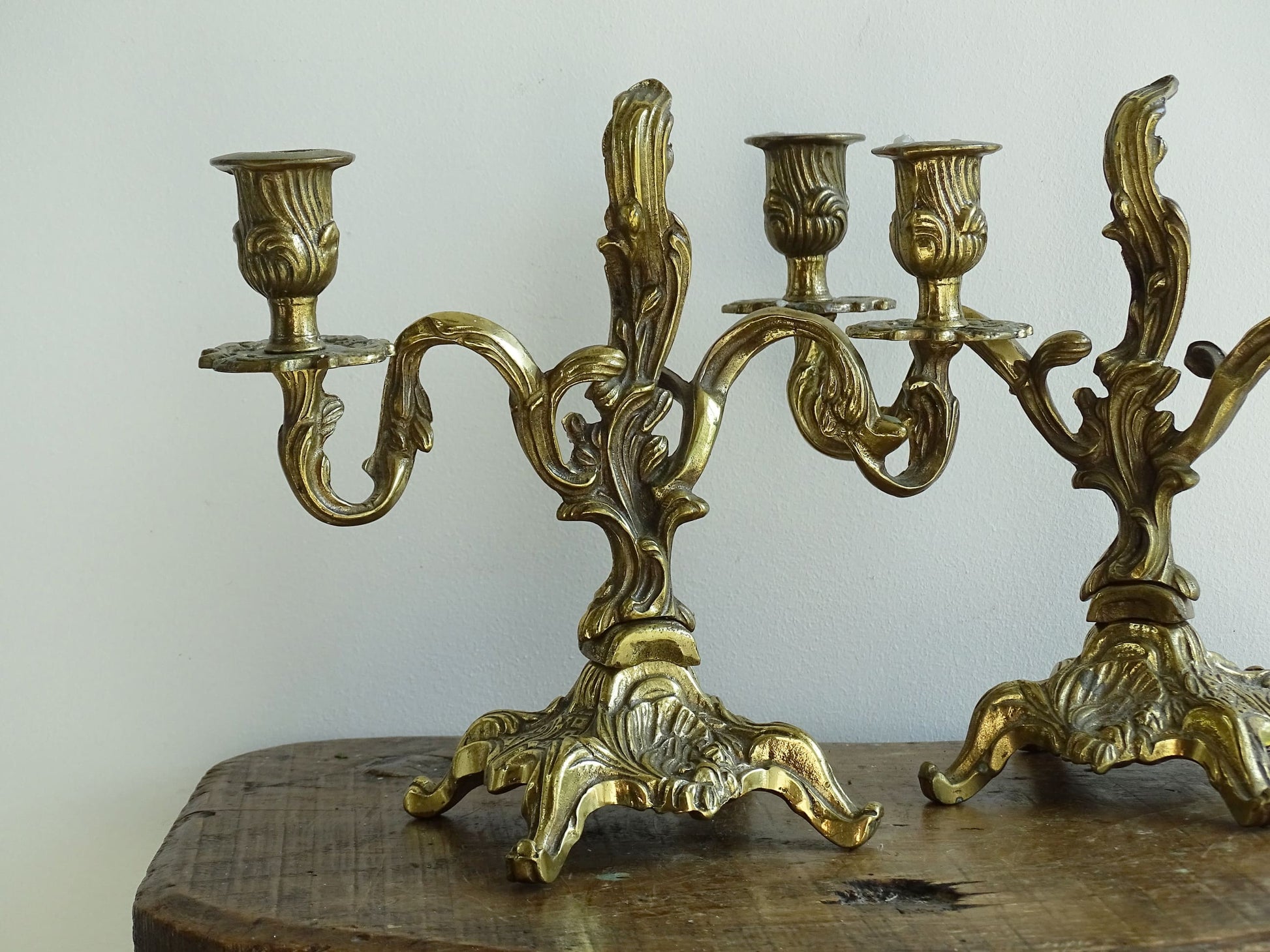 Pair of French antique brass candelabras in a rococo style. Early 20th century antique candelabras with space for two tapered candlesticks. Brass candle holders for dining table decor or living room decor.