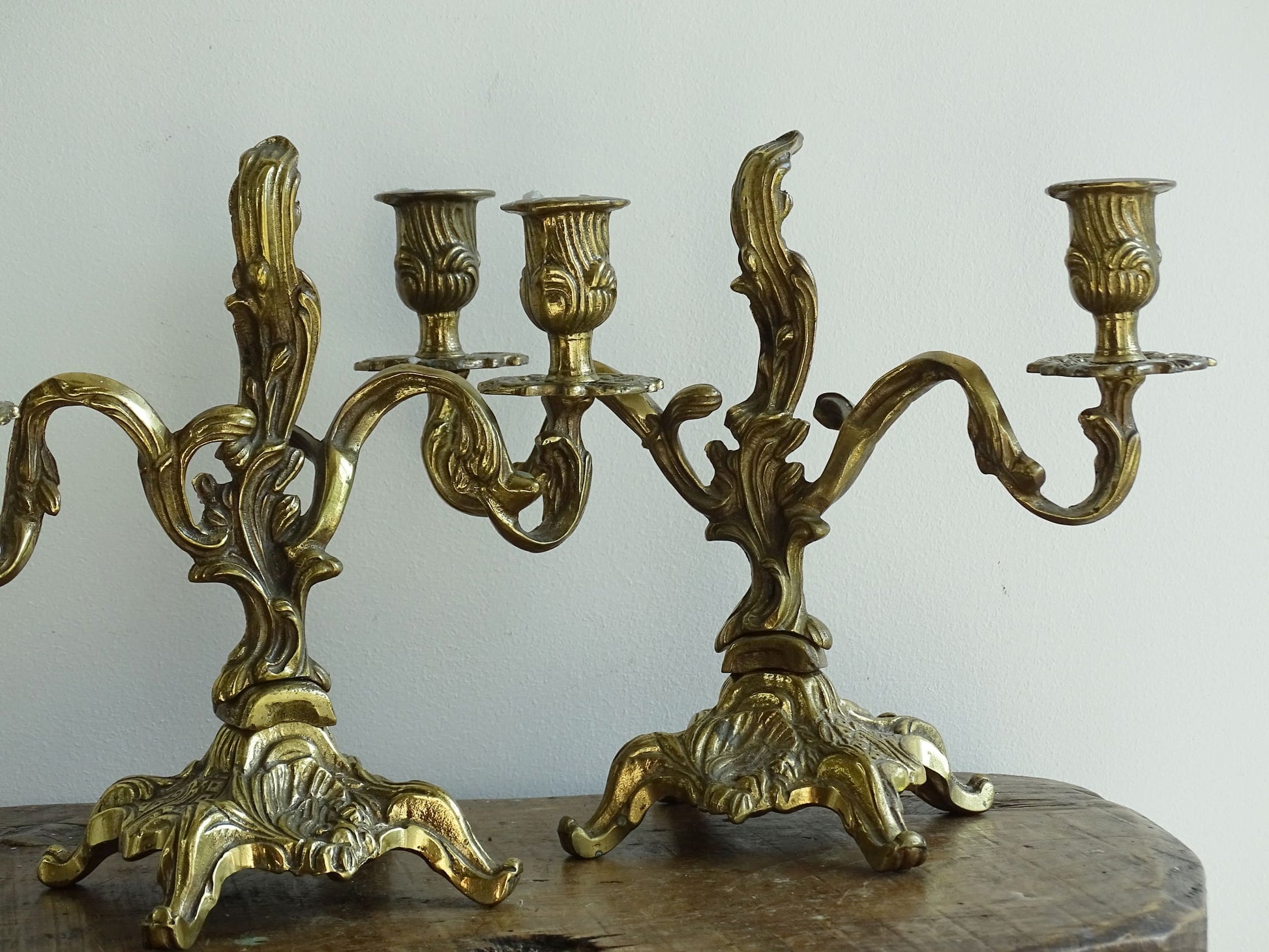 Pair of French antique brass candelabras in a rococo style. Early 20th century antique candelabras with space for two tapered candlesticks. Brass candle holders for dining table decor or living room decor.