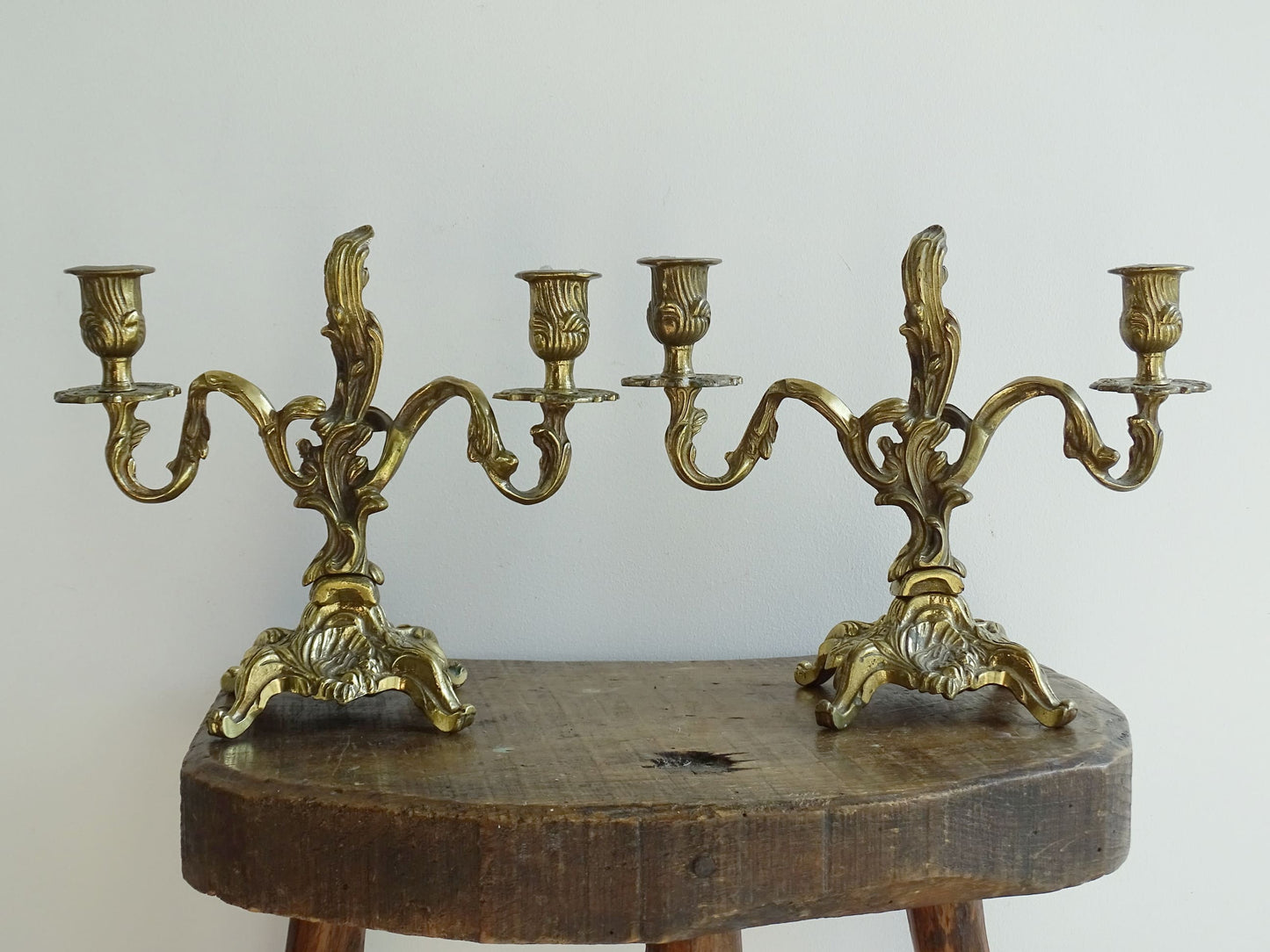 Pair of French antique brass candelabras in a rococo style. Early 20th century antique candelabras with space for two tapered candlesticks. Brass candle holders for dining table decor or living room decor.