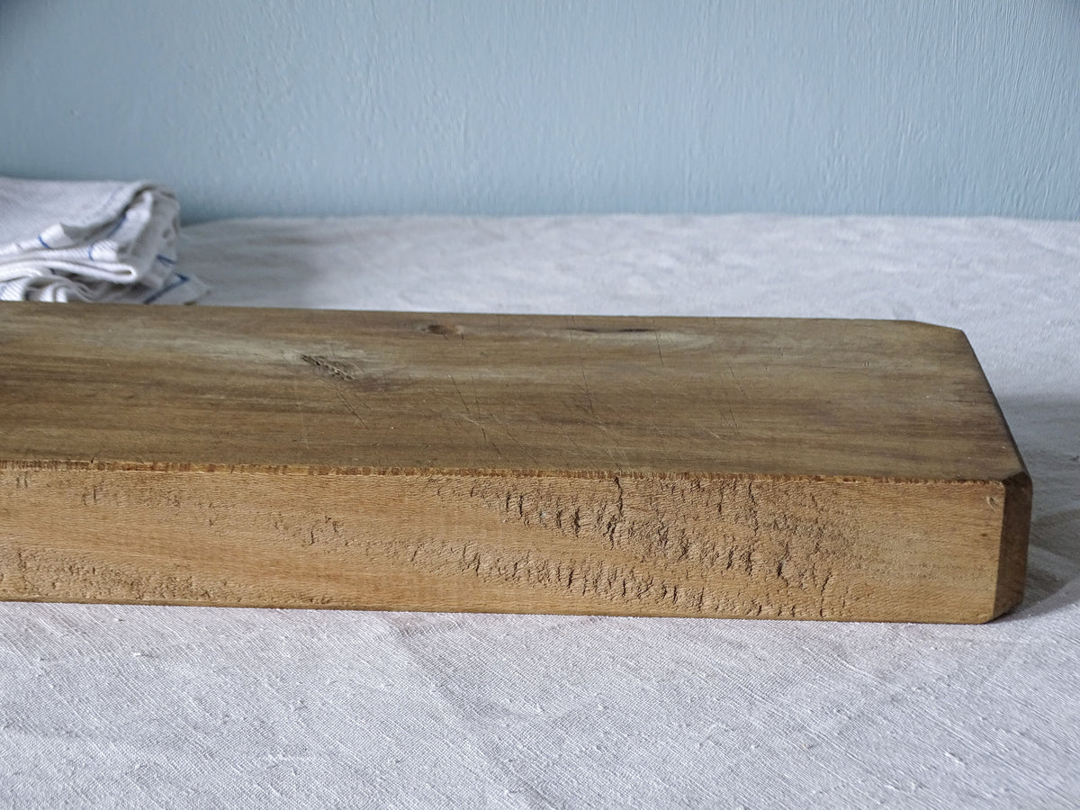 Close-up of thick vintage French wooden cutting board showing natural imperfections, worn edges and solid wood construction.