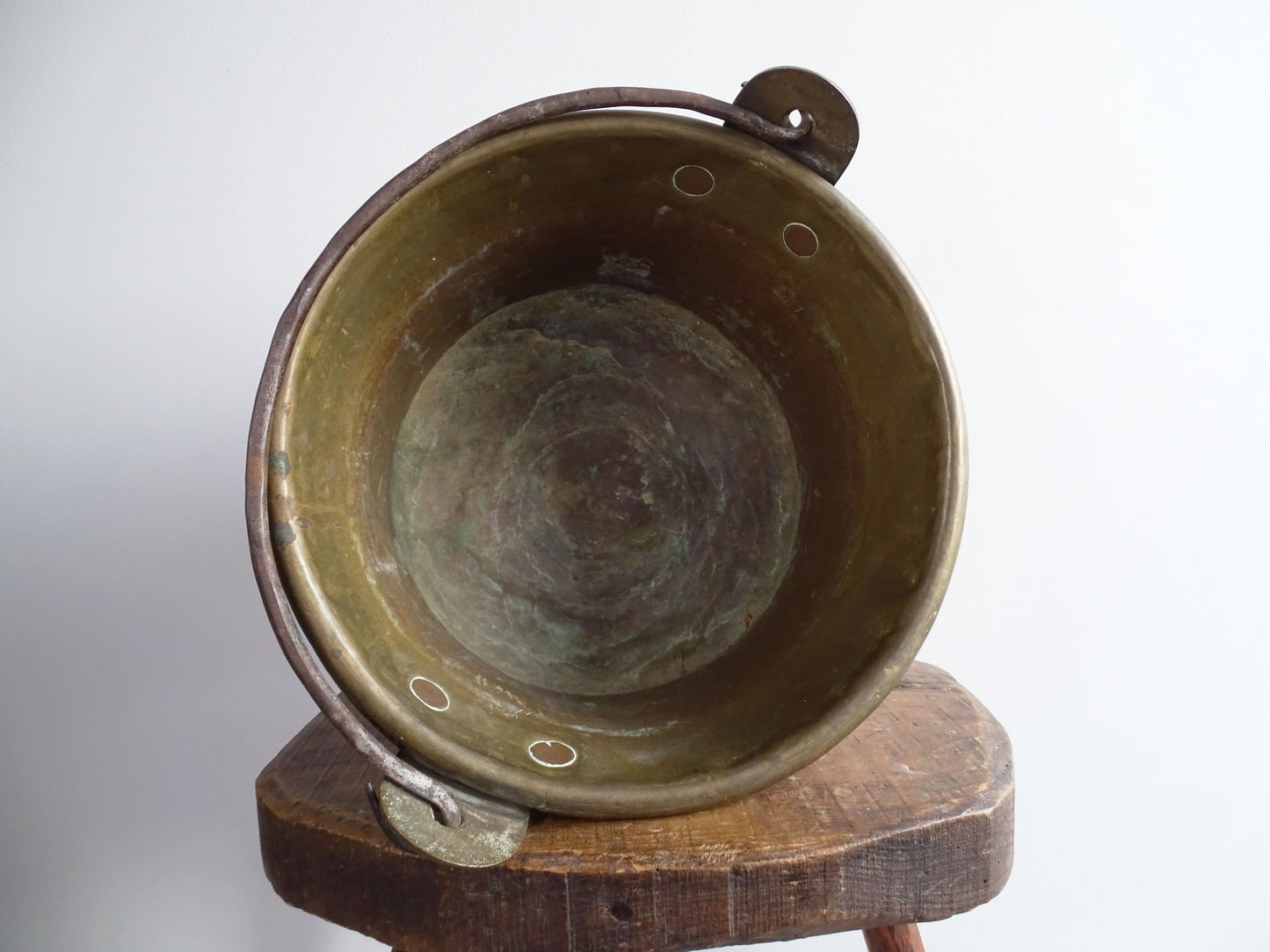 French antique brass cauldron with a hammered brass body and wrought iron handle, brass cooking pot ideal for farmhouse kitchen decor or rustic home decor, displayed on a wooden surface.