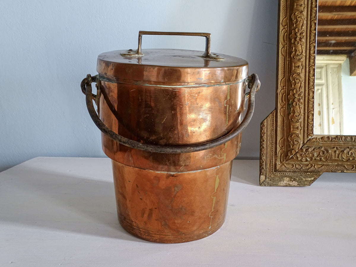 French antique copper cooking pot or cauldron with wrought iron handle, pictured next to a gold mirror