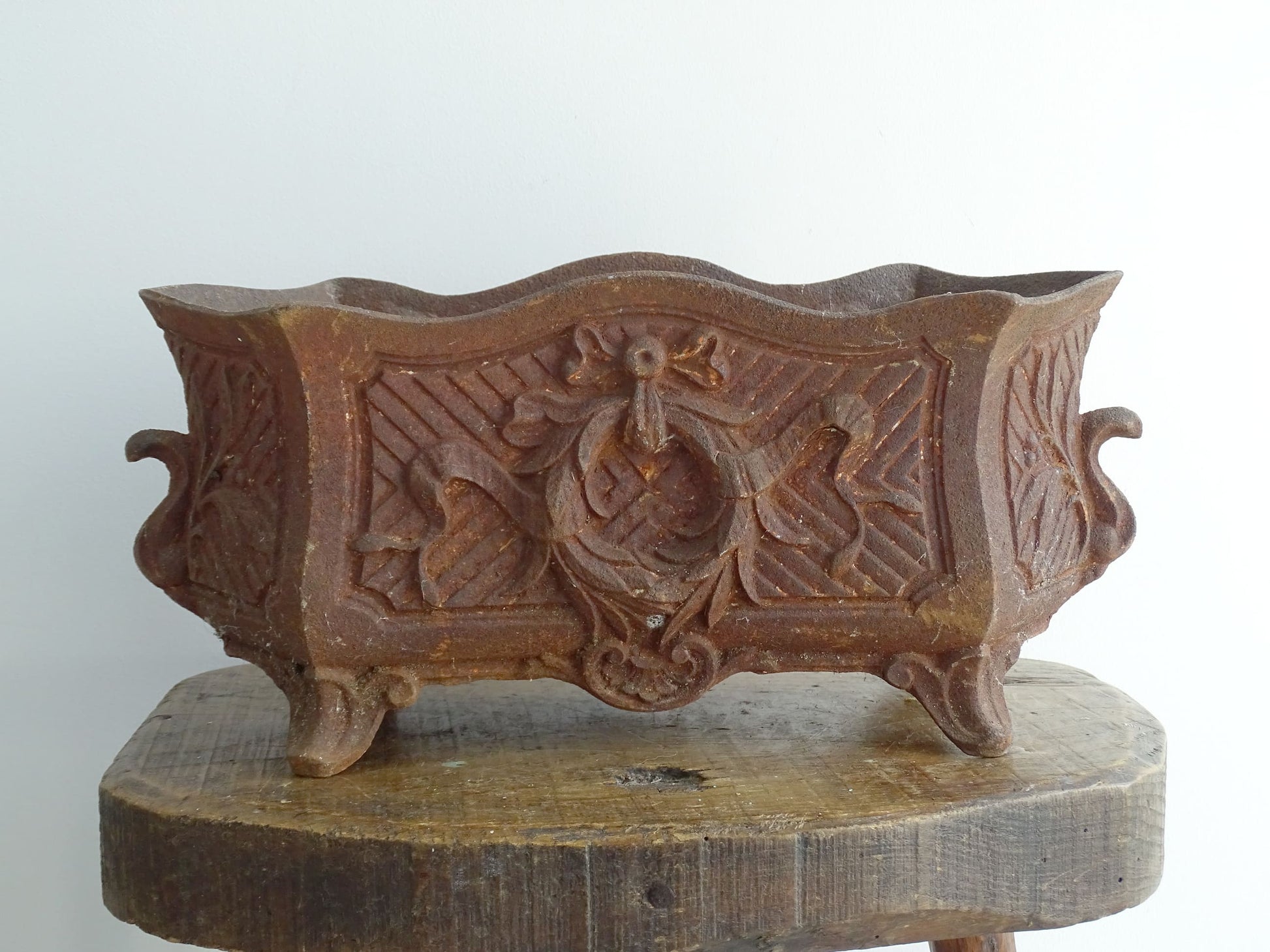 Antique French cast iron jardiniere or antique planter, 19th century, with a gorgeous patina. It is on four feet and has a wreath and ribbon motif decorating it. French outdoor decor.