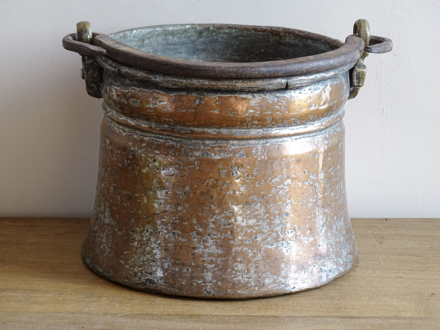 French antique tinned copper cauldron with brass detailing. A small antique copper cauldron with patina. A planter or utensil holder in a French country farmhouse kitchen.