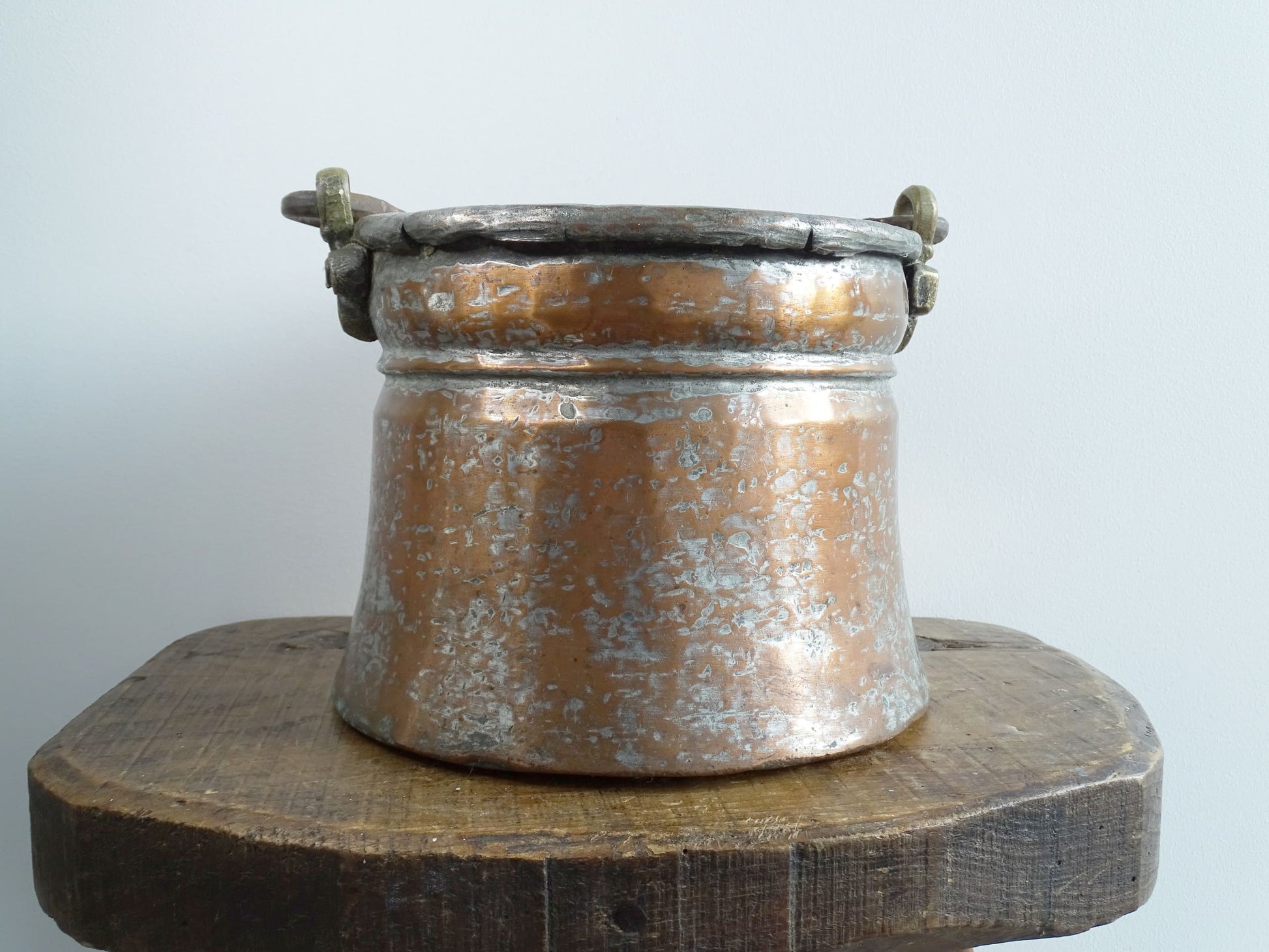 French antique tinned copper cauldron with brass detailing. A small antique copper cauldron with patina. A planter or utensil holder in a French country farmhouse kitchen.