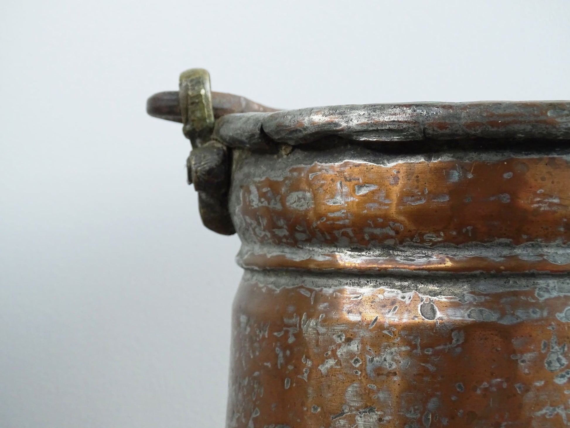 French antique tinned copper cauldron with brass detailing. A small antique copper cauldron with patina. A planter or utensil holder in a French country farmhouse kitchen.