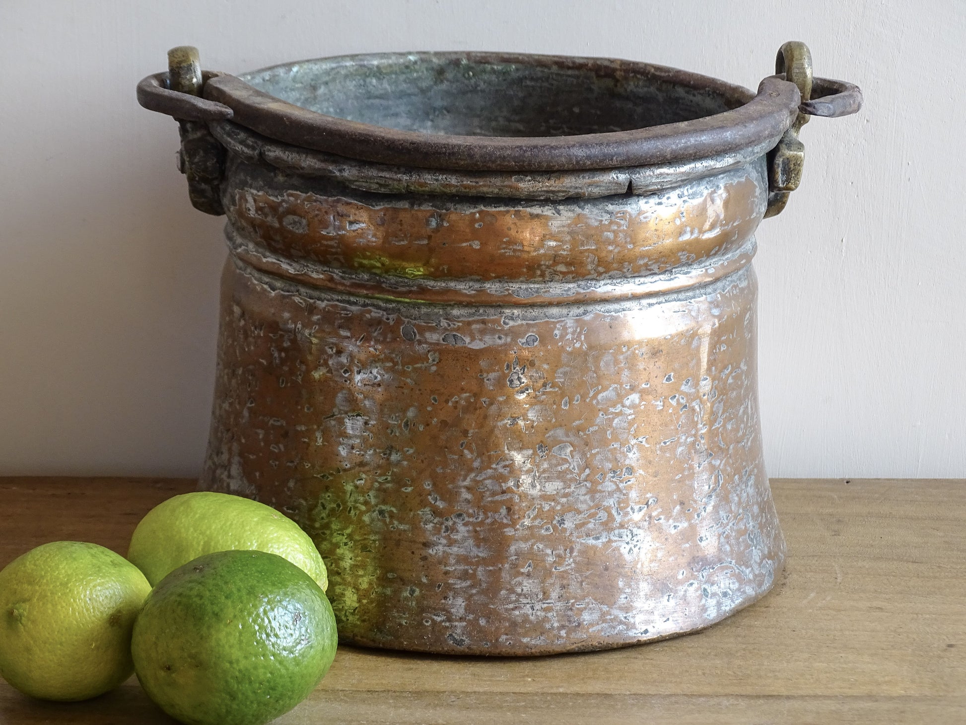 French antique tinned copper cauldron with brass detailing. A small antique copper cauldron with patina. A planter or utensil holder in a French country farmhouse kitchen.