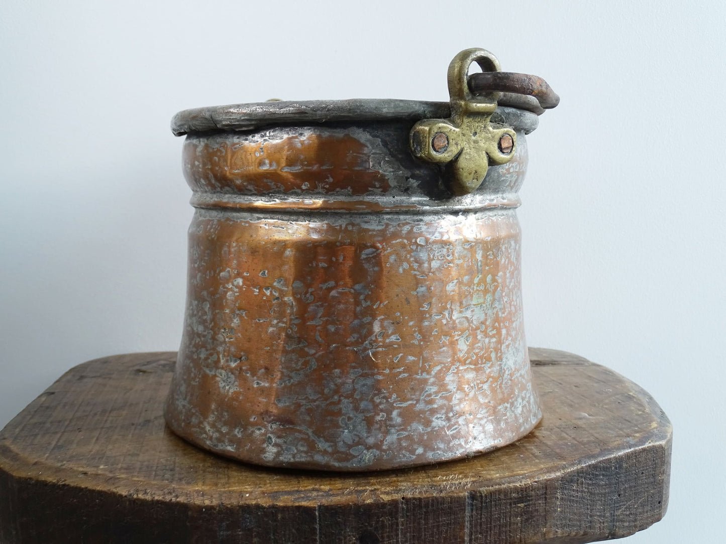 French antique tinned copper cauldron with brass detailing. A small antique copper cauldron with patina. A planter or utensil holder in a French country farmhouse kitchen.