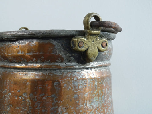 French antique tinned copper cauldron with brass detailing. A small antique copper cauldron with patina. A planter or utensil holder in a French country farmhouse kitchen.