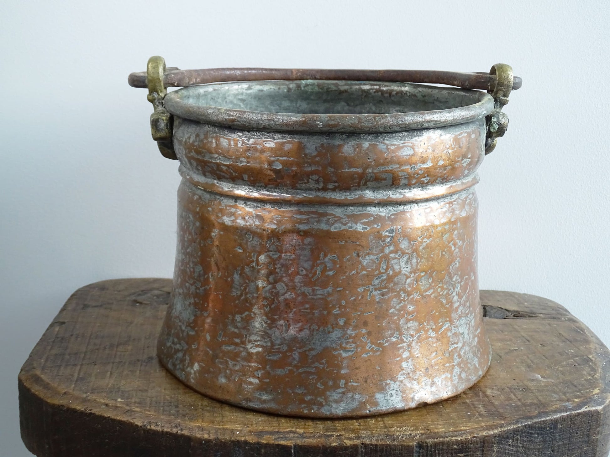 French antique tinned copper cauldron with brass detailing. A small antique copper cauldron with patina. A planter or utensil holder in a French country farmhouse kitchen.