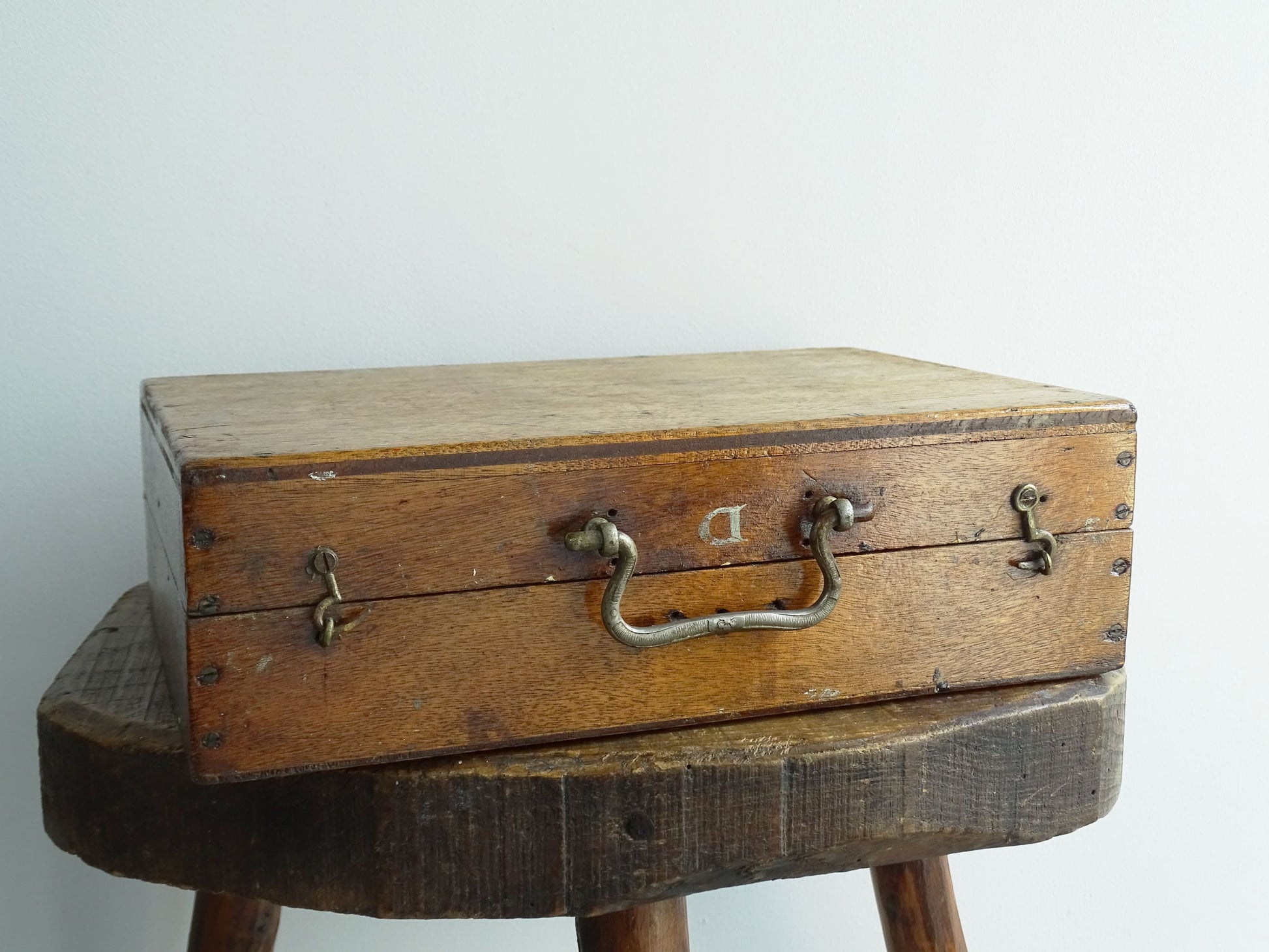 French antique paint box filled with paint brushes and painter’s tools. It has specks of paint and the outside of the wooden box has a “D” initial. The artist's box or painter's box has a rich patina.