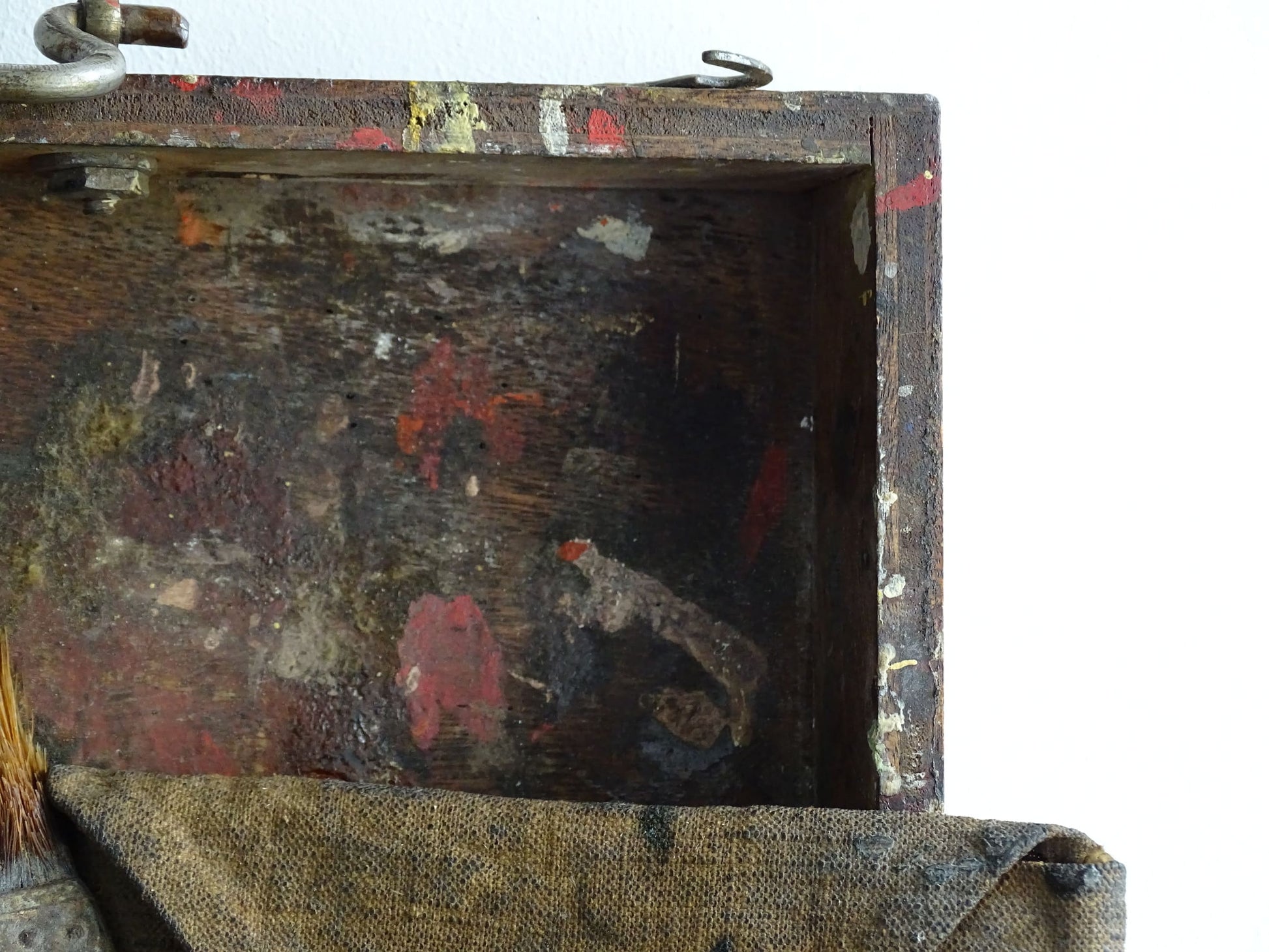 French antique paint box filled with paint brushes and painter’s tools. It has specks of paint and the outside of the wooden box has a “D” initial. The artist's box or painter's box has a rich patina.