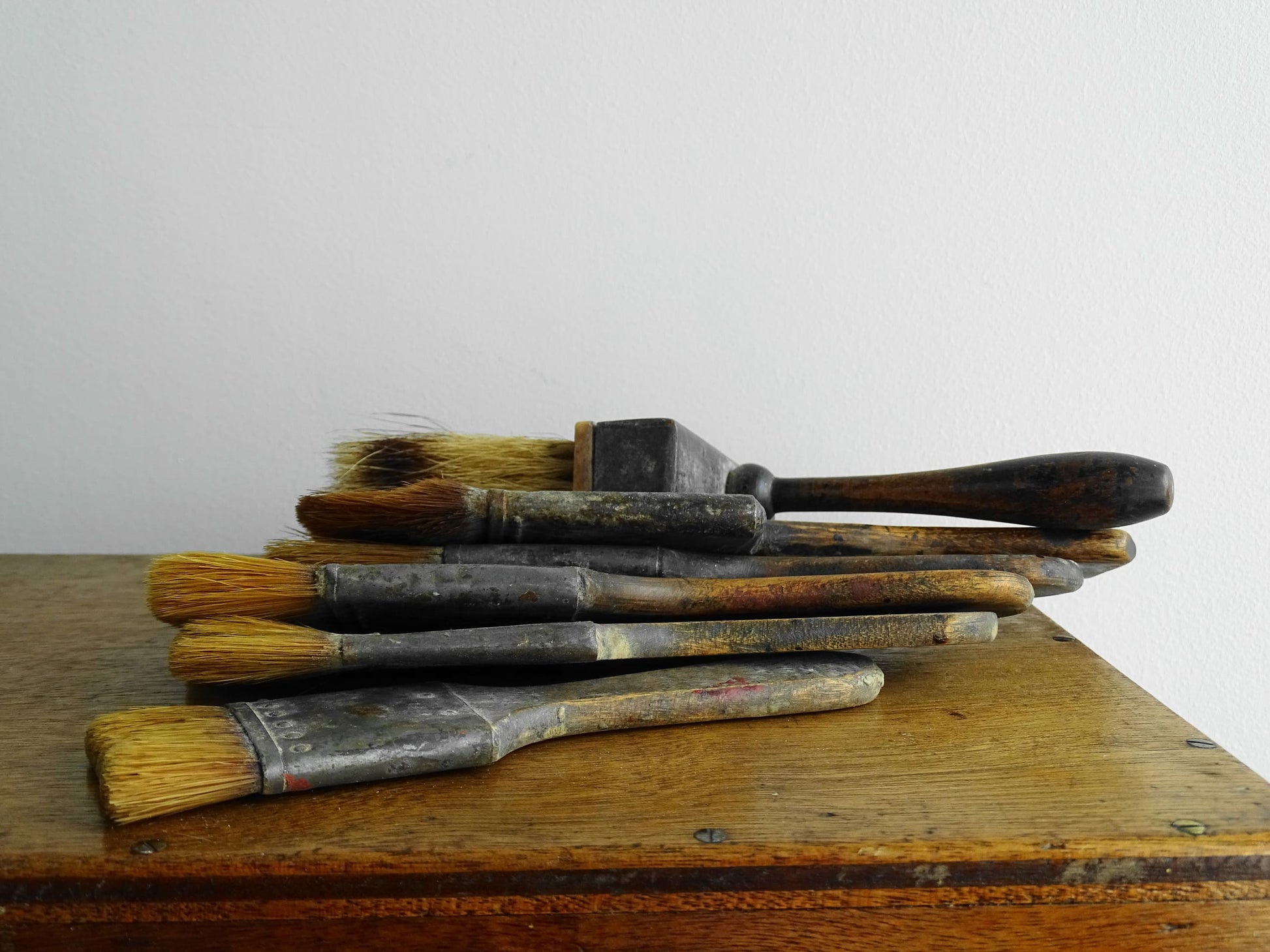 French antique paint box filled with paint brushes and painter’s tools. It has specks of paint and the outside of the wooden box has a “D” initial. The artist's box or painter's box has a rich patina.