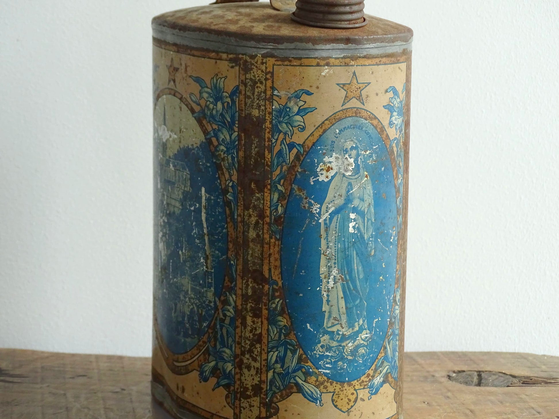 French antique Lourdes souvenir water flask. Pewter tin where the top is decorated with fleur de lis, one side depicts the cathedral (Sanctuaire de Notre-Dame de Lourdes), the other shows a crowd of people. To the side is the Virgin Mary, above her it says “Je suis l'Immaculée Conception”. The antique flask for religious decor.