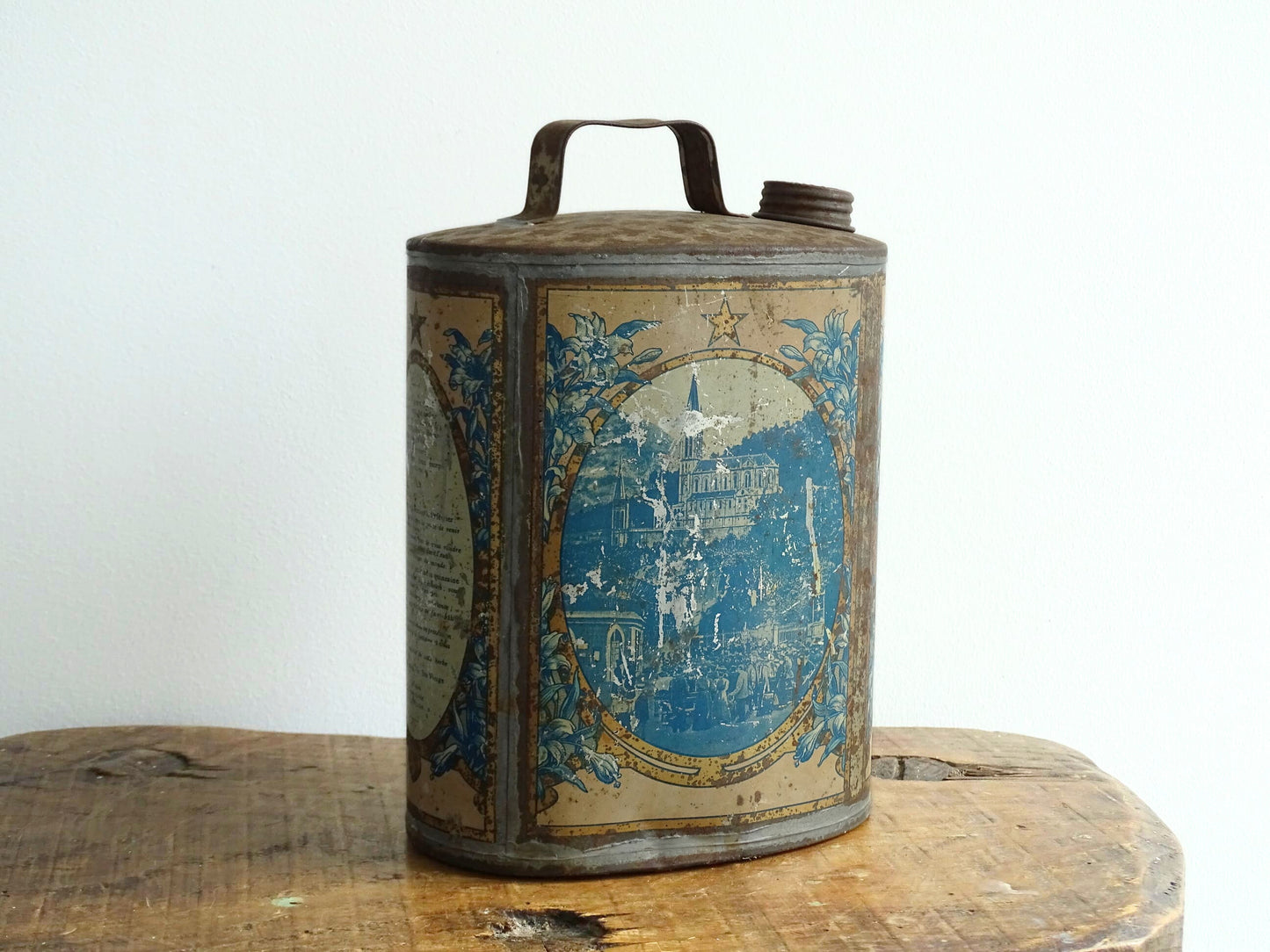 French antique Lourdes souvenir water flask. Pewter tin where the top is decorated with fleur de lis, one side depicts the cathedral (Sanctuaire de Notre-Dame de Lourdes), the other shows a crowd of people. To the side is the Virgin Mary, above her it says “Je suis l'Immaculée Conception”. The antique flask for religious decor.