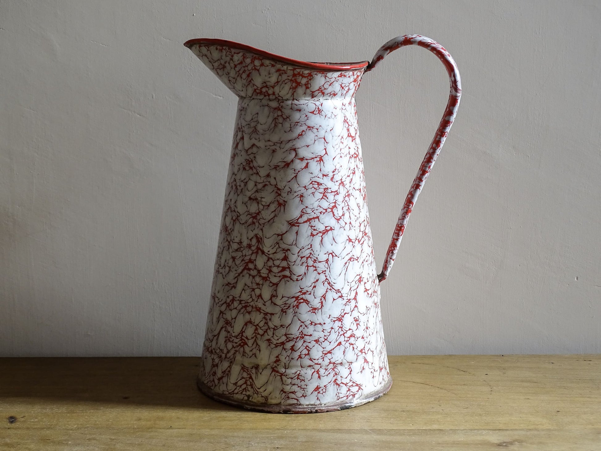 Large French vintage red and white enamelware pitcher with a large handle and spout. Tall enamel jug for farmhouse table