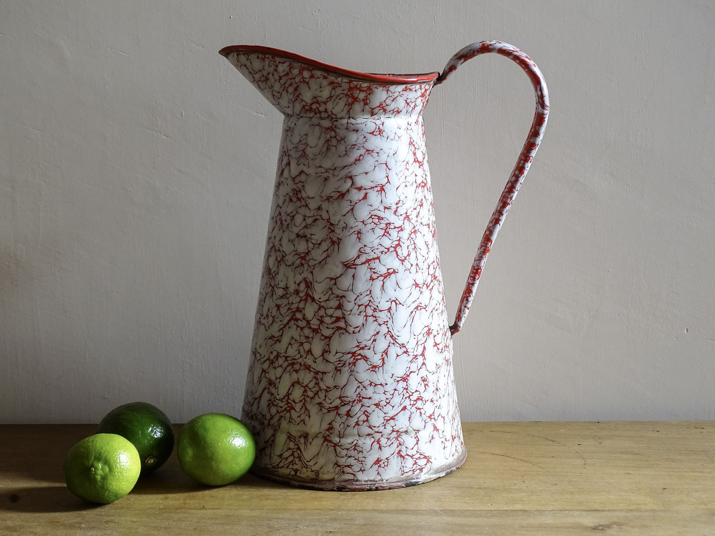 Large French vintage red and white enamelware pitcher with a large handle and spout. Tall enamel jug for farmhouse table