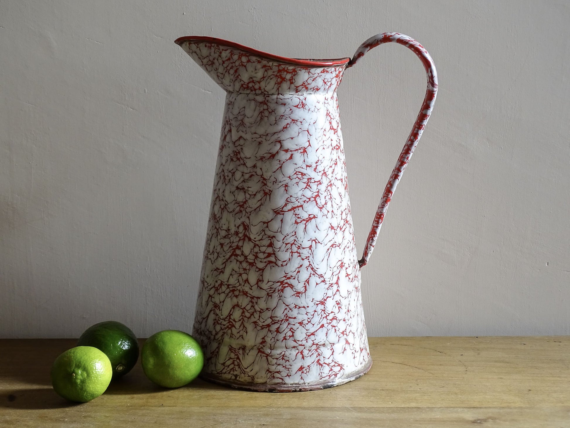 Large French vintage red and white enamelware pitcher with a large handle and spout. Tall enamel jug for farmhouse table